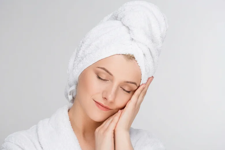 A client relaxing with her hair wrapped in a towel after treatment
